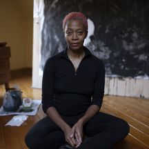 a woman sitting cross-legged on an art studio floor